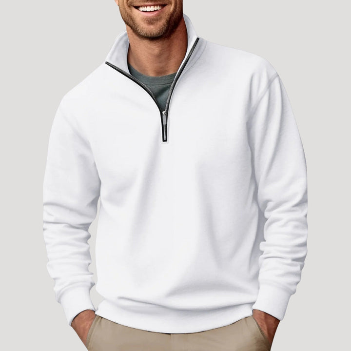 Man wearing a white Alfred quarter-zip sweatshirt with a funnel neck and relaxed fit over a grey t-shirt and chinos.