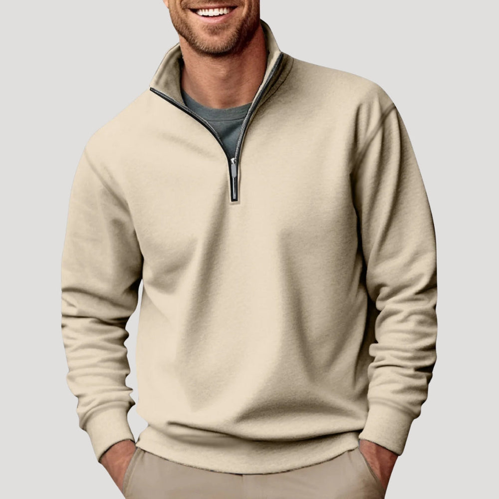 Man wearing a beige quarter-zip sweatshirt with a funnel neck and soft fabric finish over a grey t-shirt.