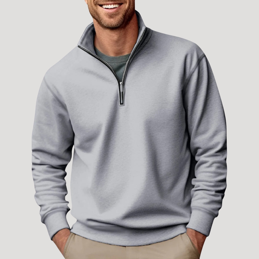 Man wearing a light grey, soft-fabric quarter-zip sweatshirt with a funnel neck and relaxed fit over a dark t-shirt.