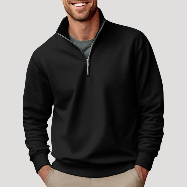 Man wearing a black Alfred quarter-zip sweatshirt with a funnel neck and relaxed fit over a grey t-shirt.