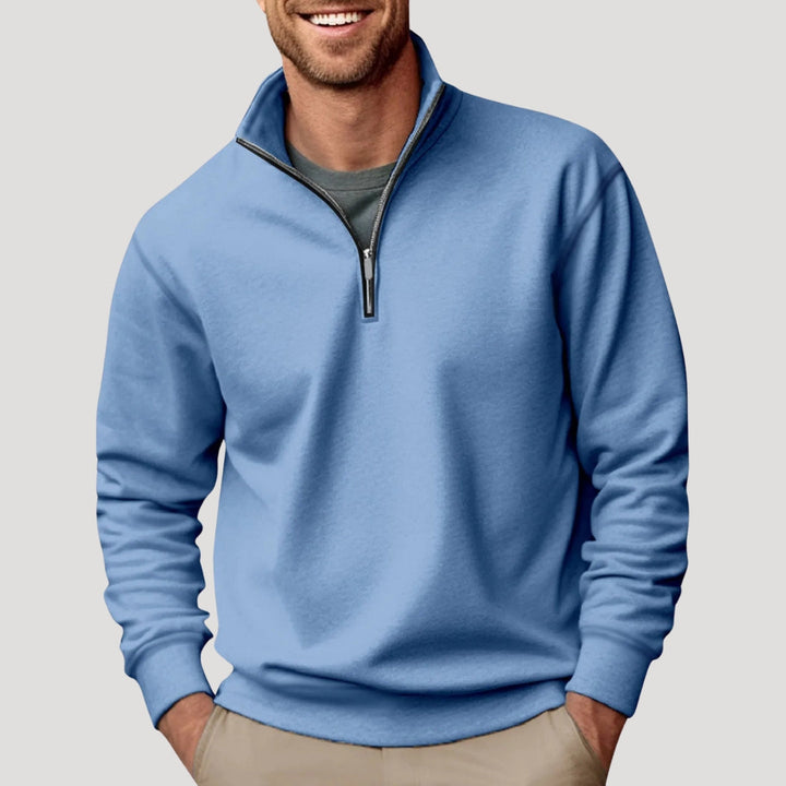 Man wearing a light blue quarter-zip sweatshirt with a funnel neck and soft, relaxed-fit fabric.