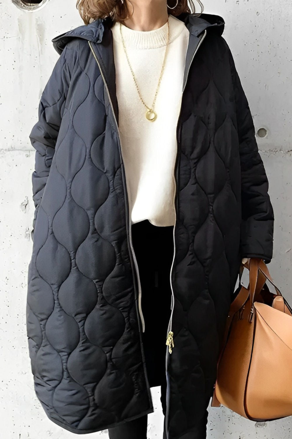 Black longline onion-quilted hooded coat with a full-length zip, worn over a white knit sweater.