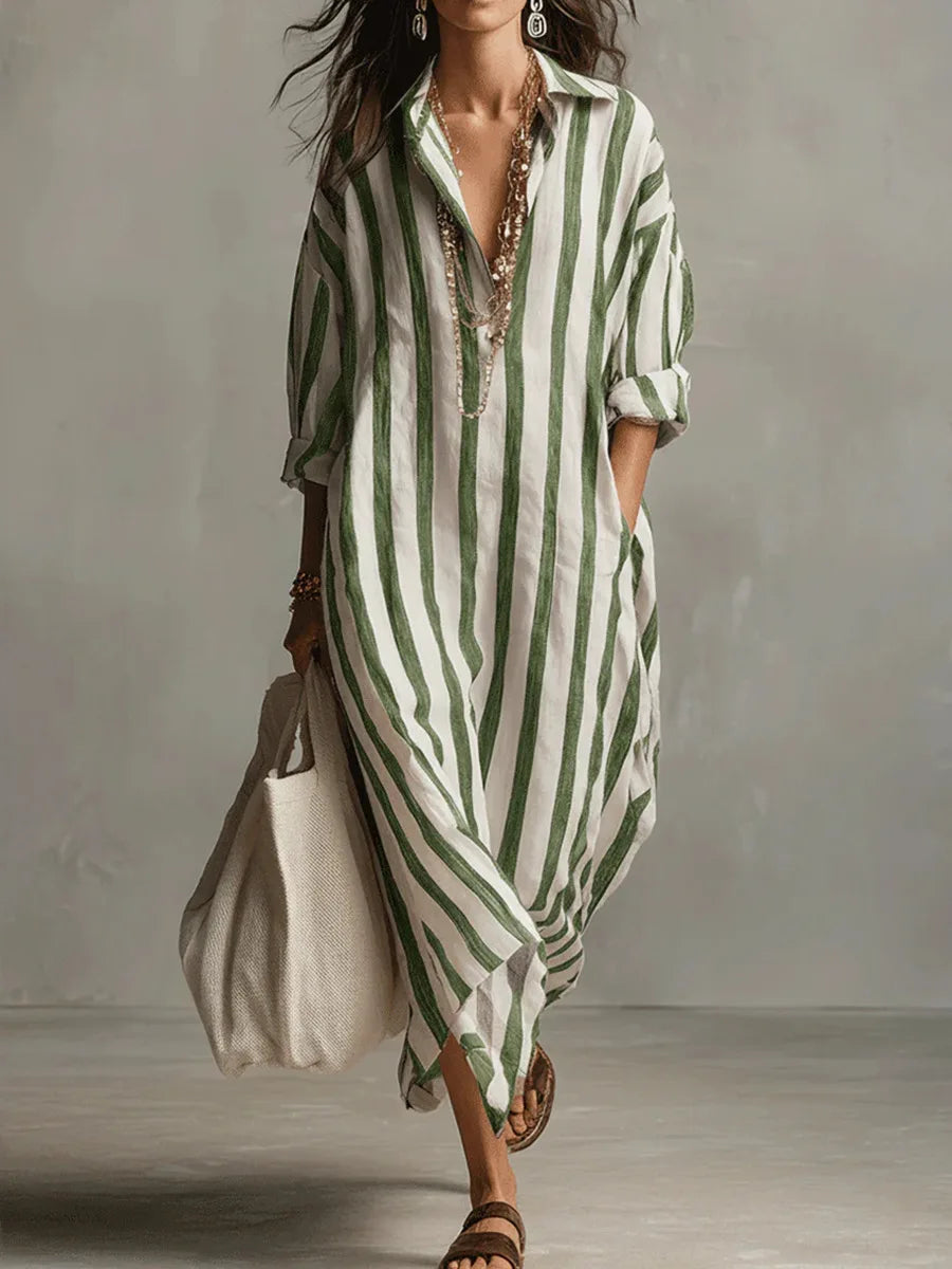 Woman wearing a loose, green and white vertical striped linen maxi shirt dress with an open collar and long sleeves.