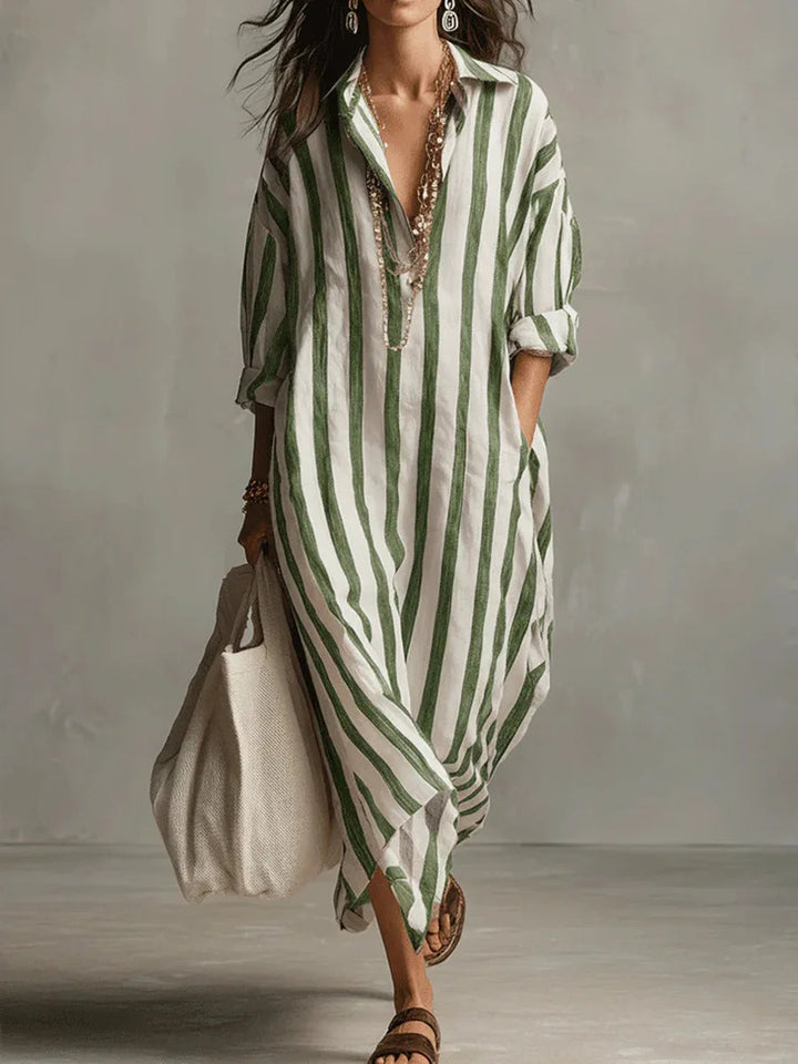 Woman wearing a loose, green and white vertical striped linen maxi shirt dress with an open collar and long sleeves.