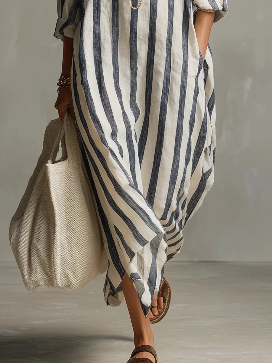 Woman wearing a breezy, loose-fit maxi shirt dress in white and navy blue vertical stripes, paired with a large tote bag.