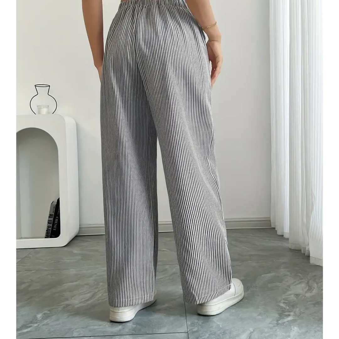 Woman wearing black and white striped linen wide-leg trousers with a comfortable drawstring waist and relaxed fit.