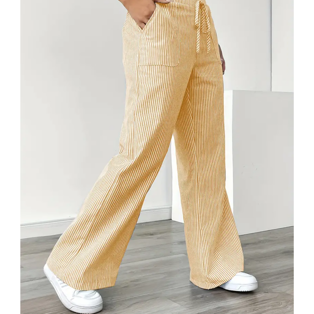 Yellow and white striped linen wide-leg trousers with a drawstring waist and side pockets, styled with white trainers.