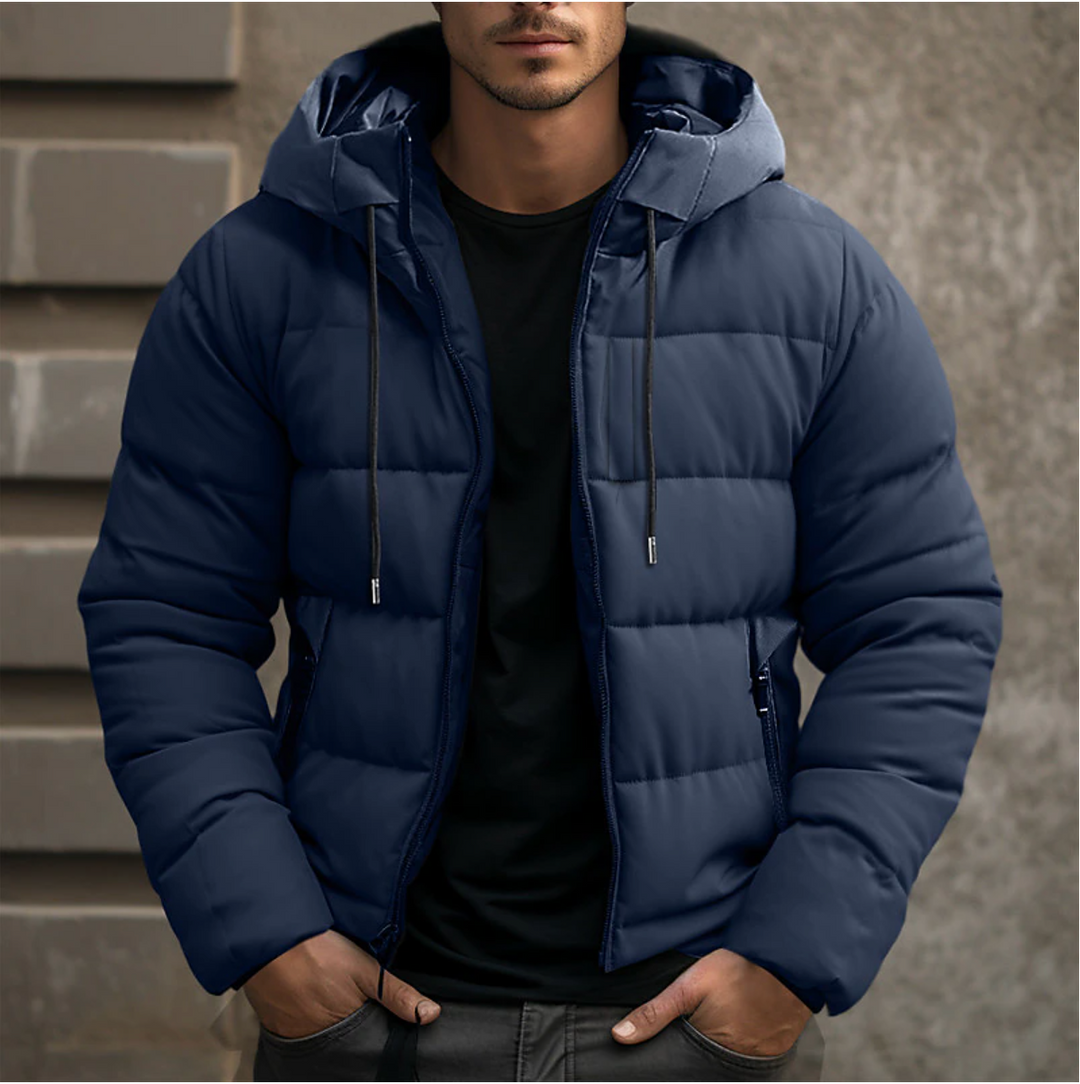 Navy blue men's hooded puffer jacket with quilted insulation, full-length zip, and drawstring hood over a black t-shirt.