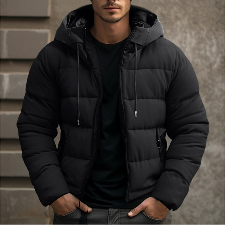 Man wearing a black quilted puffer jacket with an adjustable drawstring hood and full-length zip fastening.