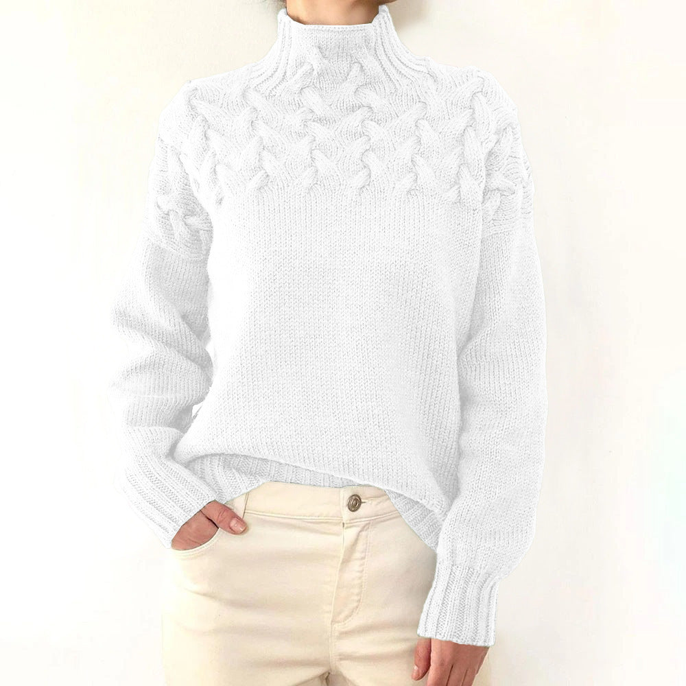 White cable knit turtleneck jumper with a braided yoke, relaxed fit, and ribbed cuffs worn with cream trousers.