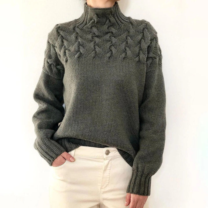 Olive green cable knit turtleneck jumper with a braided yoke design, ribbed cuffs, and a relaxed fit.