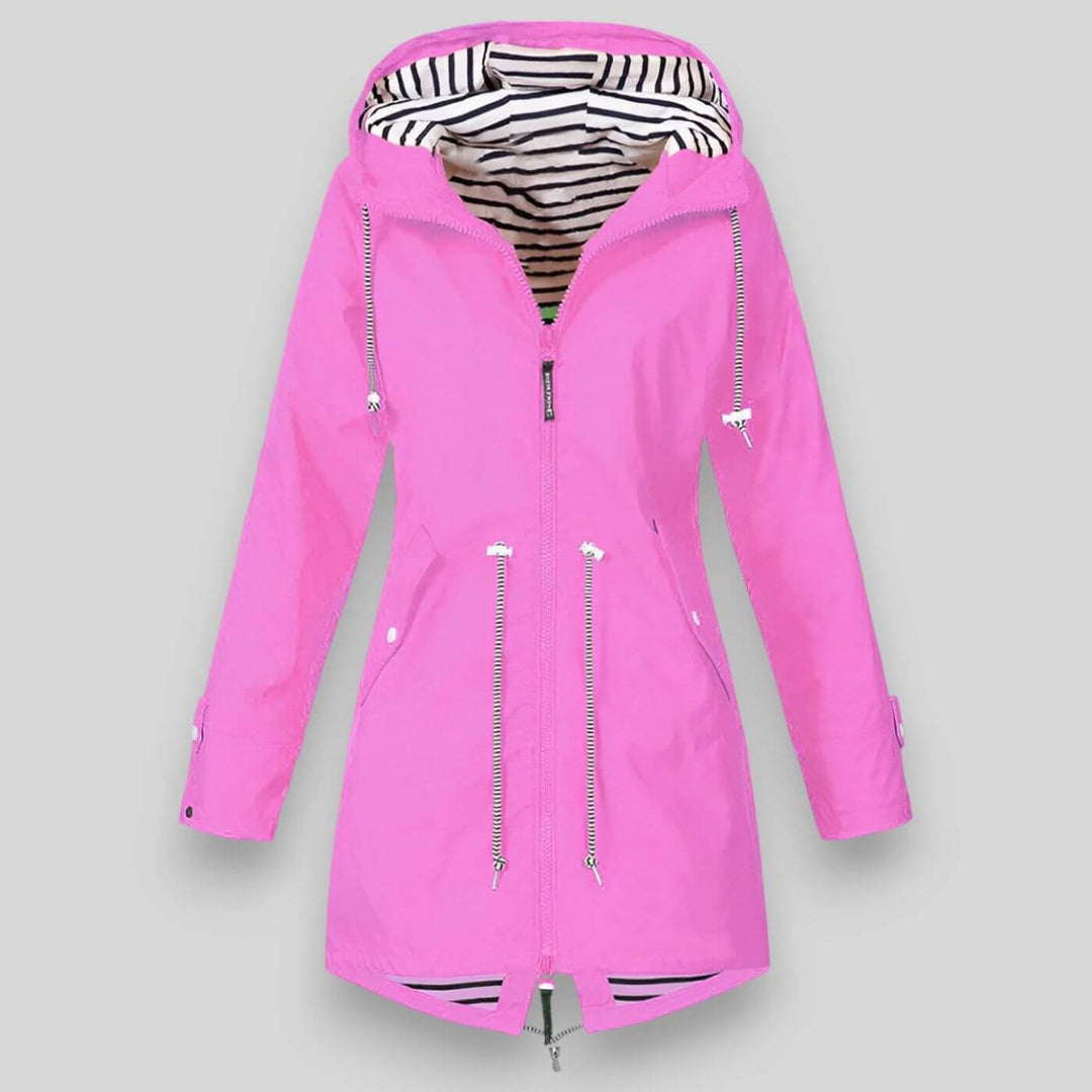 Bright pink longline waterproof raincoat with an adjustable hood, drawcord waist, and nautical black-and-white striped lining.
