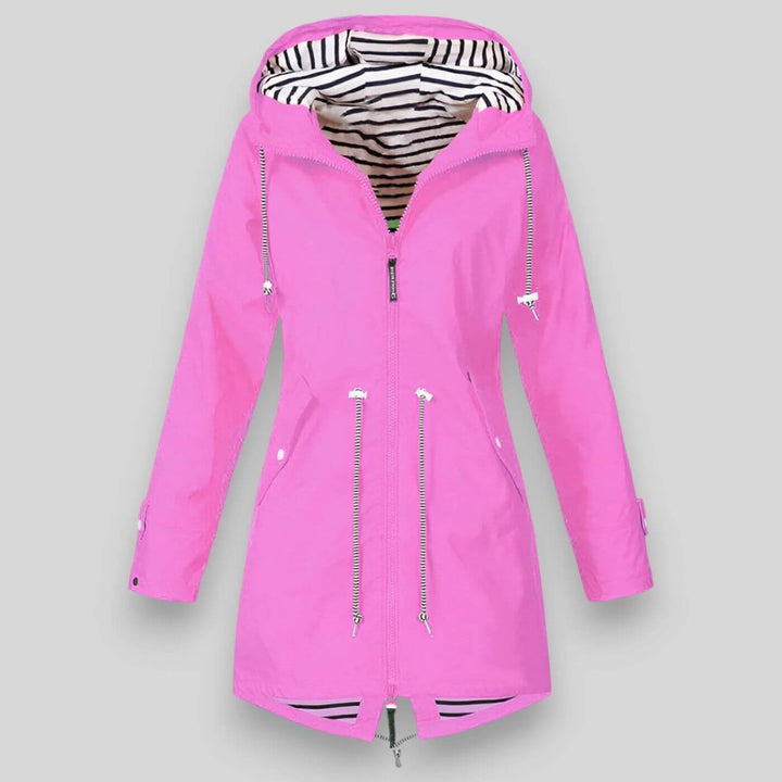 Bright pink longline waterproof raincoat with an adjustable hood, drawcord waist, and nautical black-and-white striped lining.
