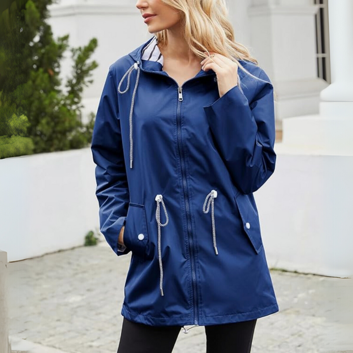 Woman wearing a navy blue waterproof longline raincoat with an adjustable hood, drawcord waist, and striped lining.