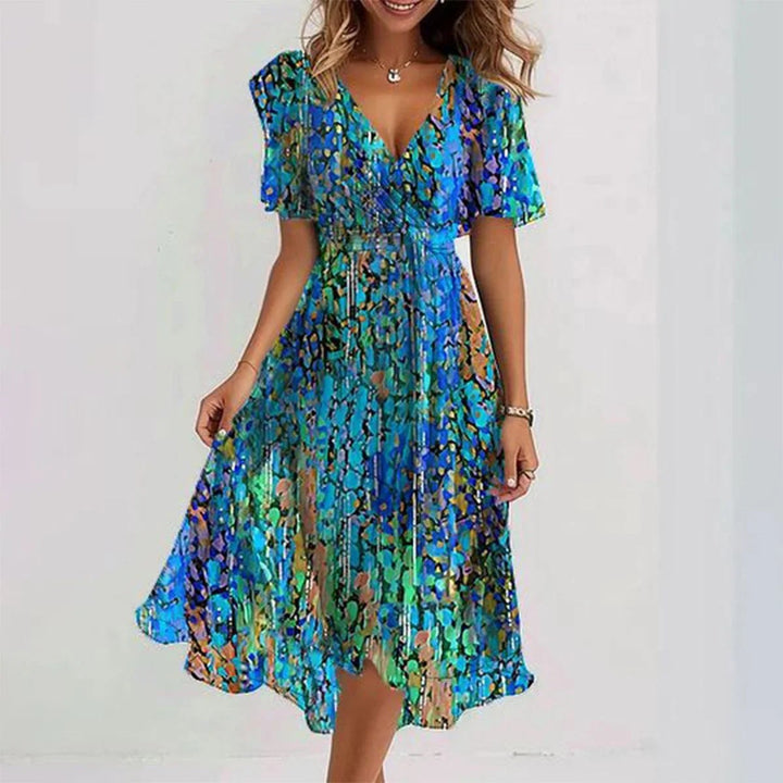 Beatrice women's flowy summer dress in a vibrant blue, green, and orange abstract print with a V-neck and short sleeves.