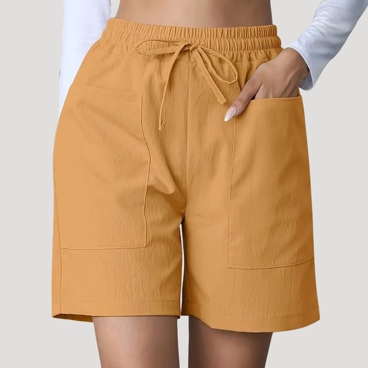 Mustard yellow wide-leg shorts with an elastic drawstring waist and large front patch pockets.
