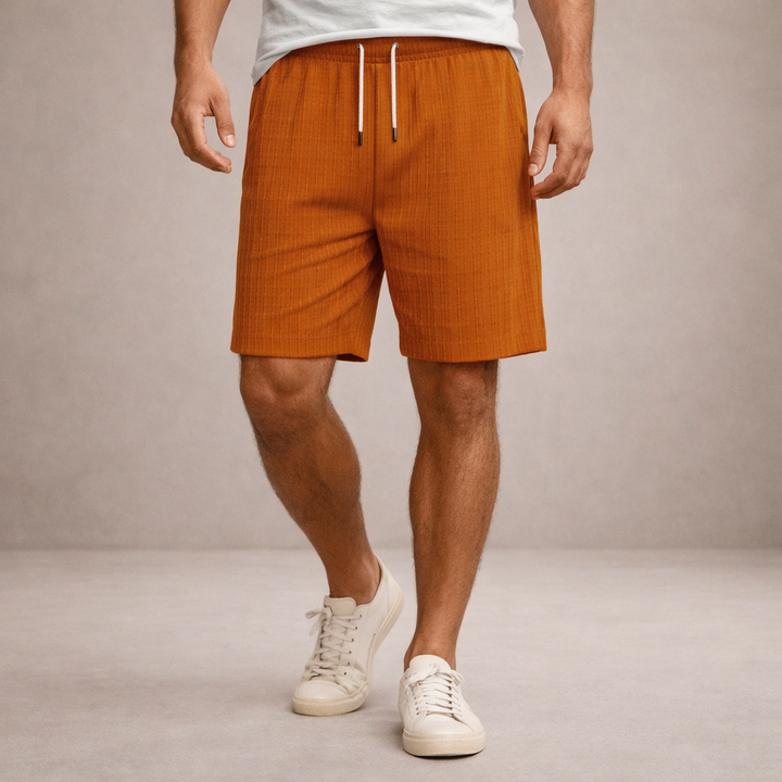 Men wearing rust-orange linen-look drawstring shorts with an elasticated waist and a clean, straight-hemmed silhouette.