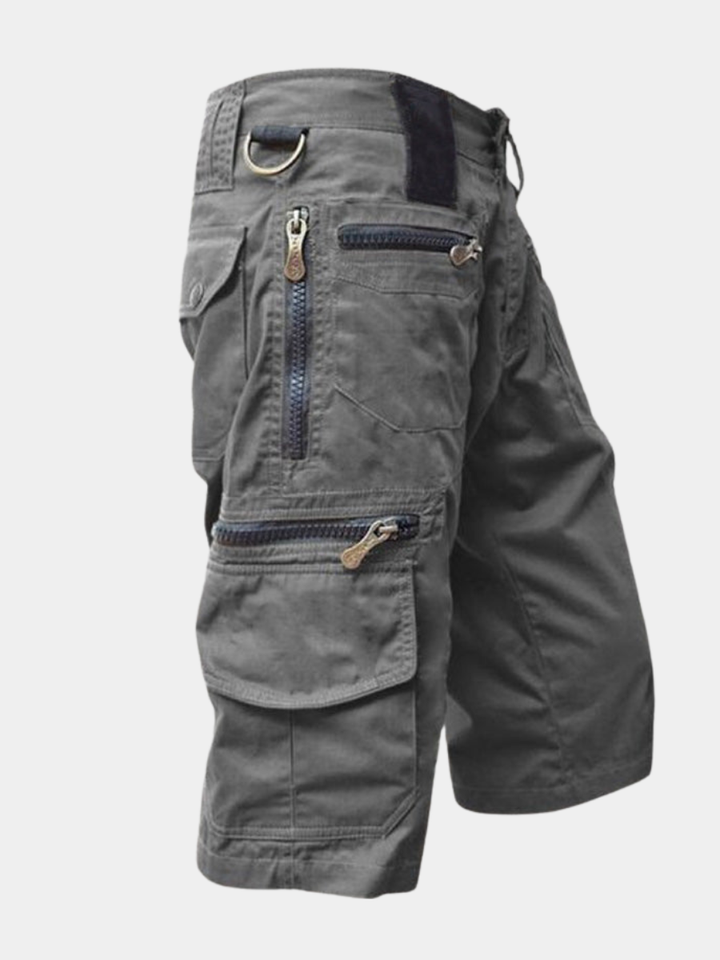 Charcoal grey cotton cargo shorts featuring multiple zip and flap pockets, a D-ring, and a structured, modern fit.