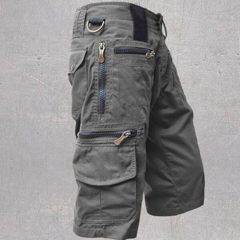 Dark grey cotton cargo shorts featuring multiple zip and flap pockets, a D-ring, and a structured, modern fit.