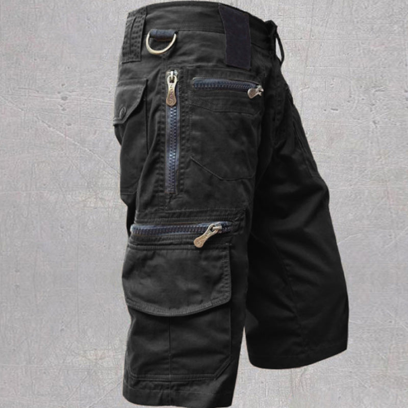 Black cotton cargo shorts featuring multiple zip and flap pockets, a D-ring attachment, and an adjustable drawstring waist.