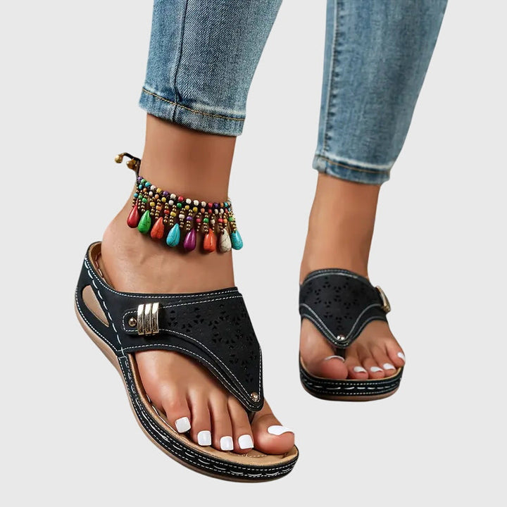 Bonnie black orthopedic wedge sandals with decorative cutouts and gold buckle detail, worn with jeans.