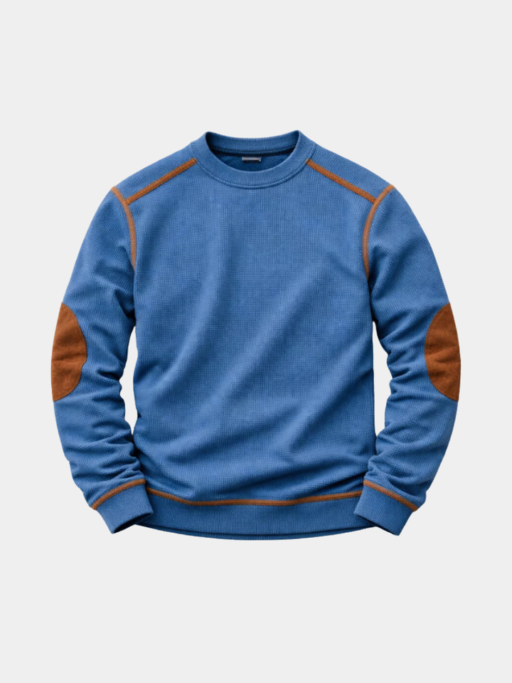 Blue waffle-knit crew neck jumper featuring brown contrast elbow patches and shoulder detailing.