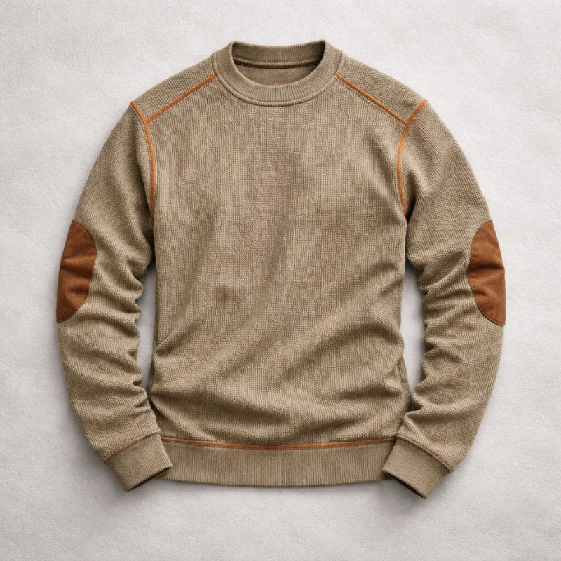 Tan waffle-knit crew neck jumper featuring contrast brown suede elbow patches and ribbed trim on a light background.