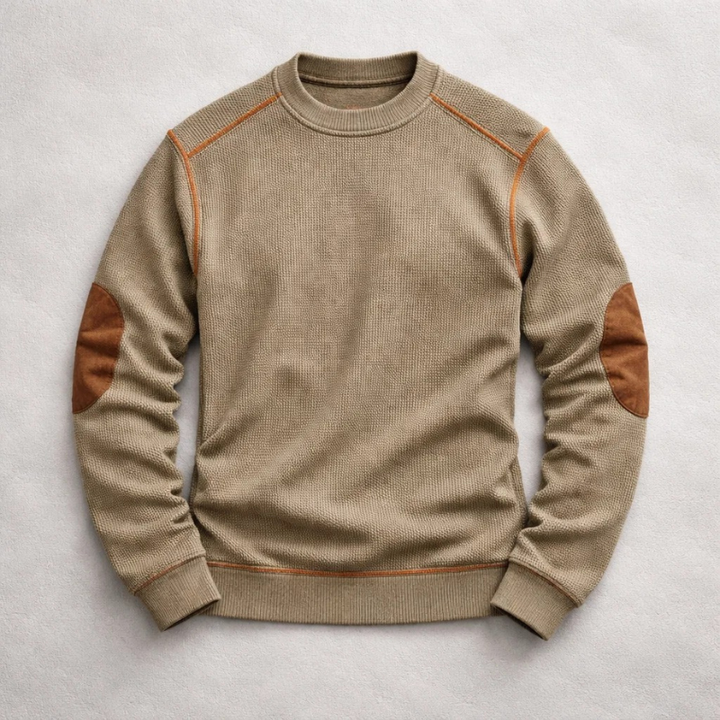 Tan waffle-knit crew neck jumper featuring contrast brown suede elbow patches and ribbed trim on a light background.