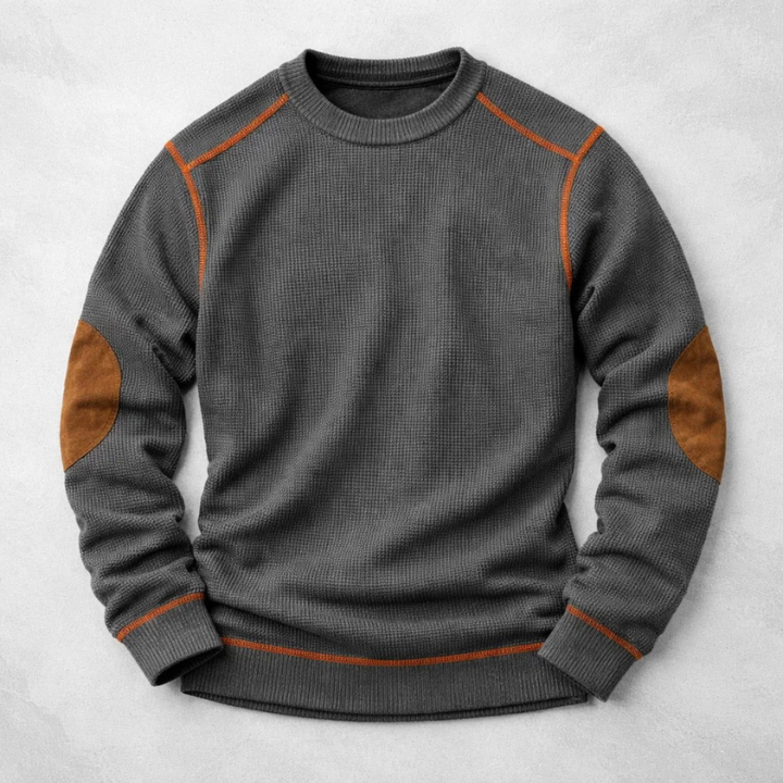 Charcoal grey waffle-knit crew neck jumper with contrast orange stitching and brown suede elbow patches.