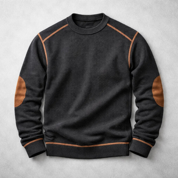 Black waffle-knit crew neck jumper with brown contrast elbow patches and matching trim details on a grey background.