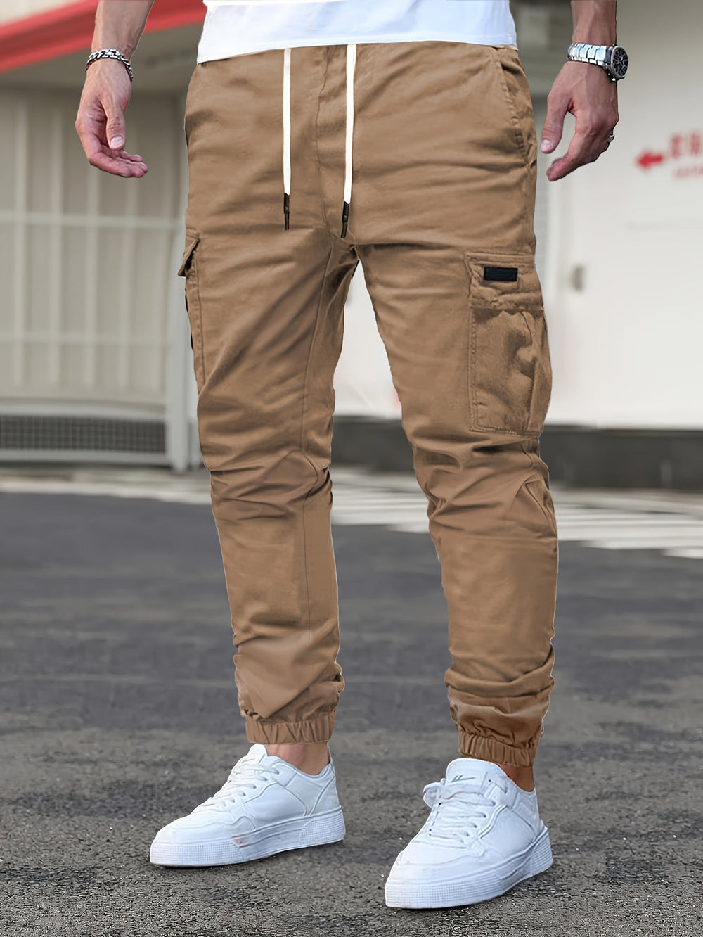 Tan men's cargo joggers with a drawstring waist, side pockets, and elasticated cuffed hems worn with white trainers.