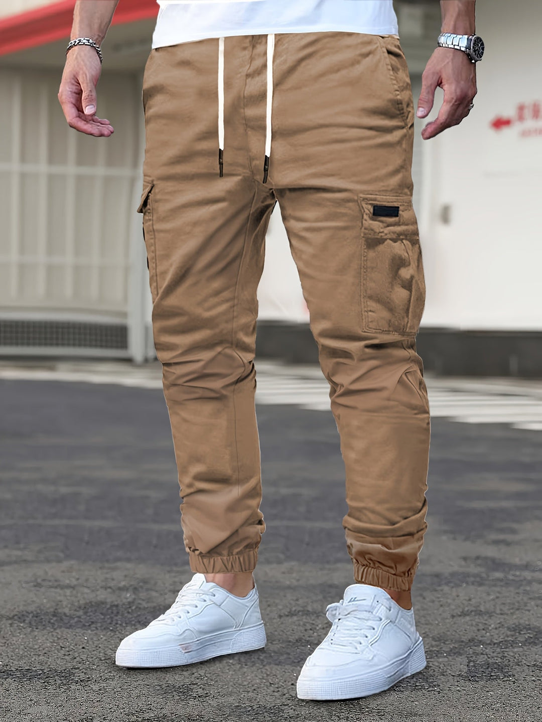 Tan men's cargo joggers with a drawstring waist, side pockets, and elasticated cuffed hems worn with white trainers.