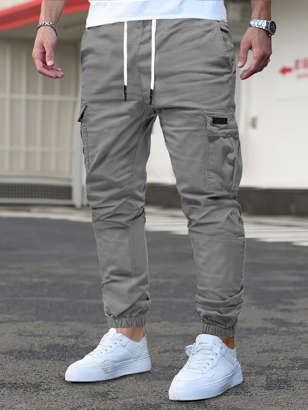 Grey men's cargo joggers with a drawstring waist, side pockets, and cuffed ankles worn with white trainers.