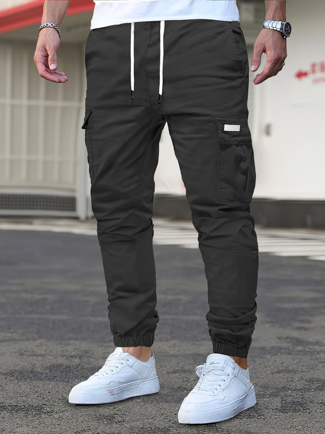 Men's black cargo joggers with a drawstring waist, side pockets, and cuffed ankles, styled with white trainers.