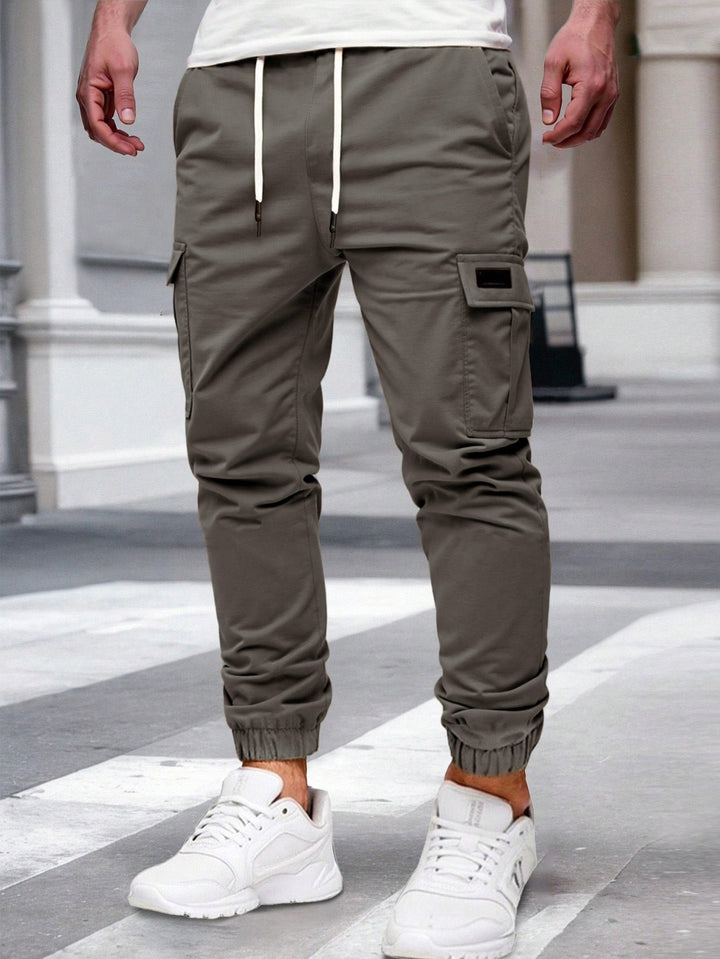 Olive green men's cargo joggers with a drawstring waist, side pockets, and elasticated cuffed hems.