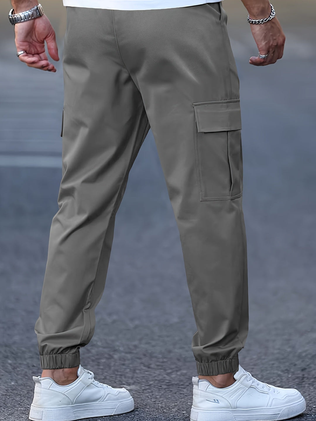 Olive green men's cargo joggers with side pockets, elasticated cuffed ankles, and a tapered fit worn with white trainers.