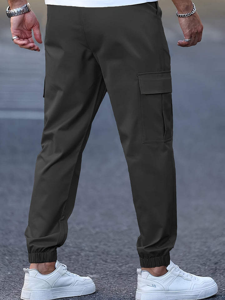 Dark olive green cargo joggers with side pockets, elasticated cuffed ankles, and a tapered fit worn with white trainers.