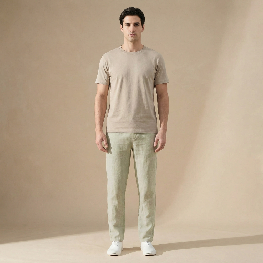Man wearing sage green straight-leg linen trousers and a beige t-shirt against a neutral studio background.