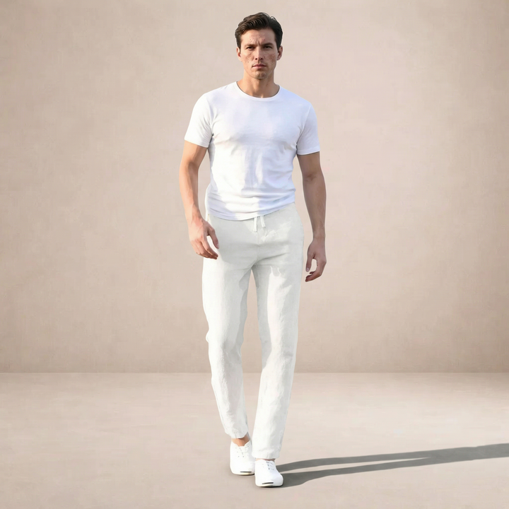 Man wearing white lightweight linen straight-leg trousers with a drawstring waist and a simple white t-shirt.