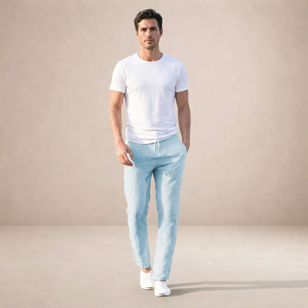 Man wearing light blue straight-leg linen trousers with a drawstring waist, paired with a white t-shirt and sneakers.