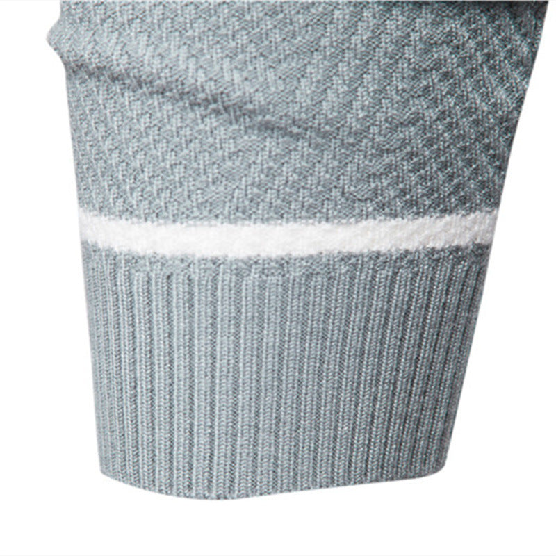 Close-up of a grey textured knit jumper sleeve featuring a white contrast stripe and a ribbed cuff.