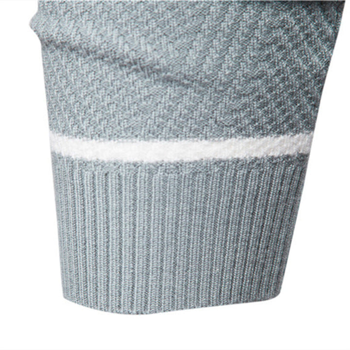 Close-up of a grey textured knit jumper sleeve featuring a white contrast stripe and a ribbed cuff.