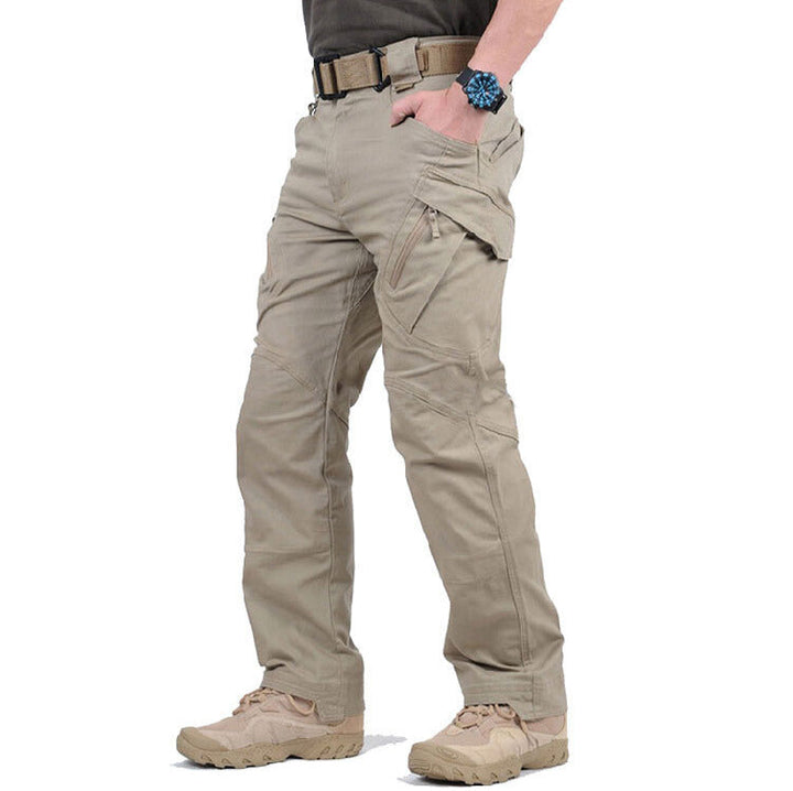 Beige men's tactical cargo trousers with reinforced knees, multiple zip pockets, and a rugged, durable outdoor design.