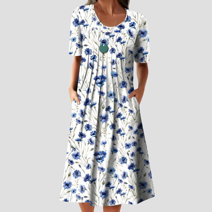 Women's short-sleeve midi dress with a white and blue floral print, pleated bodice, scoop neckline, and side pockets.