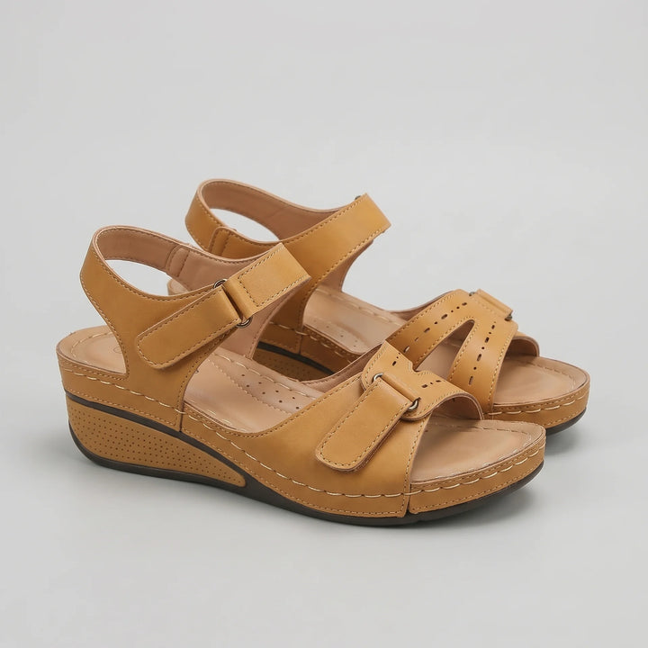 Pair of tan sandals on a light gray background