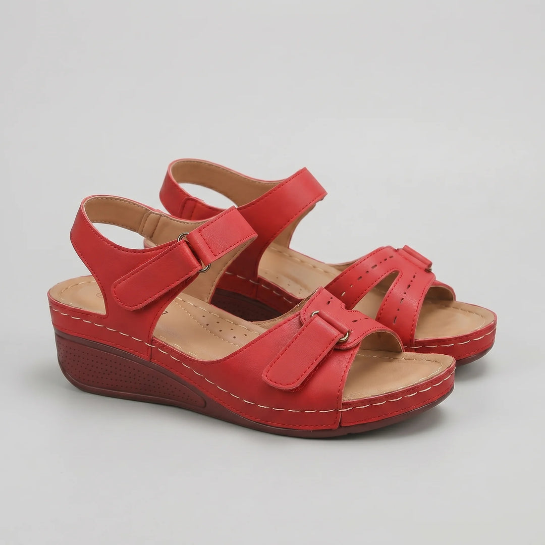 Red sandals with a wedge heel on a light gray background
