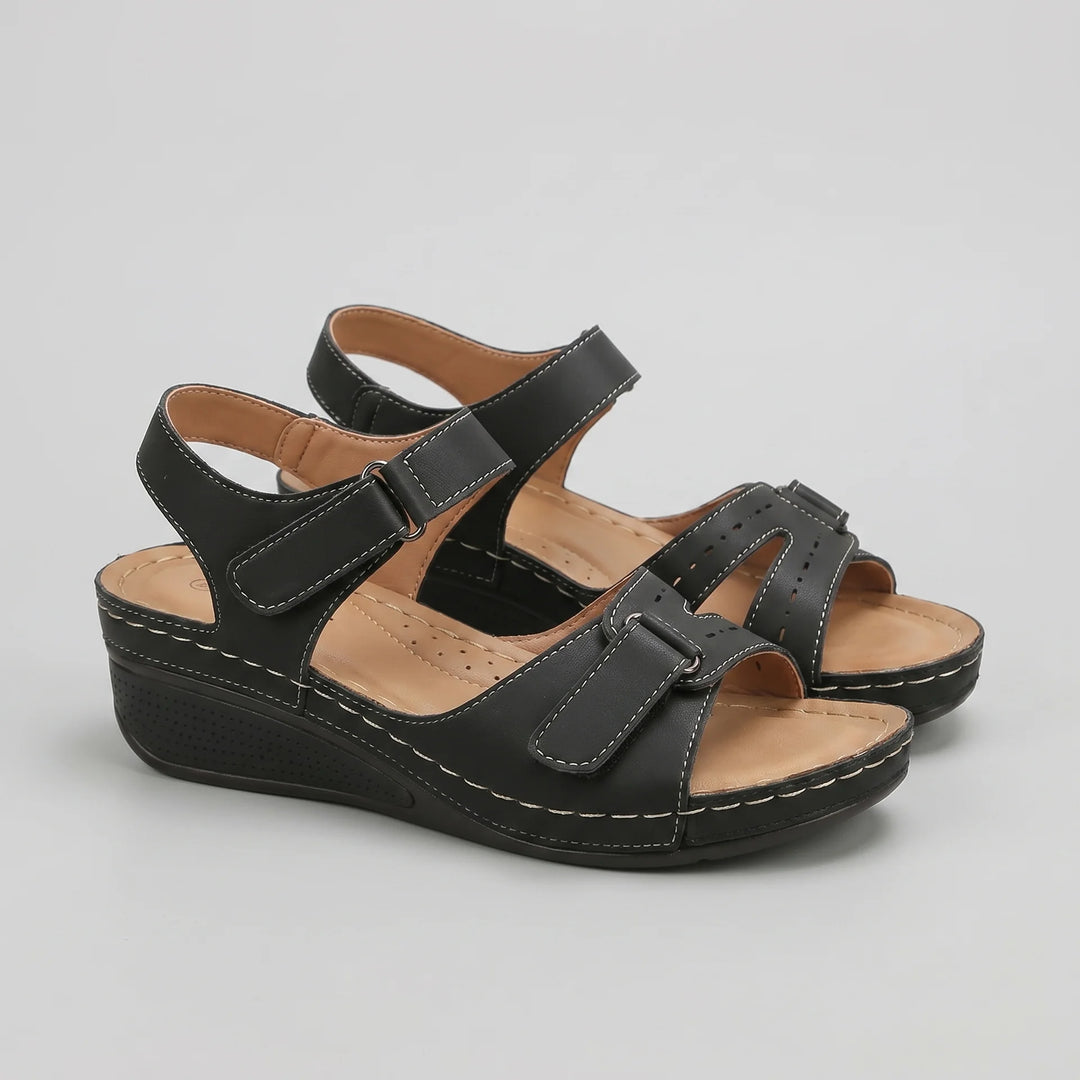 Black sandals with brown soles on a gray background
