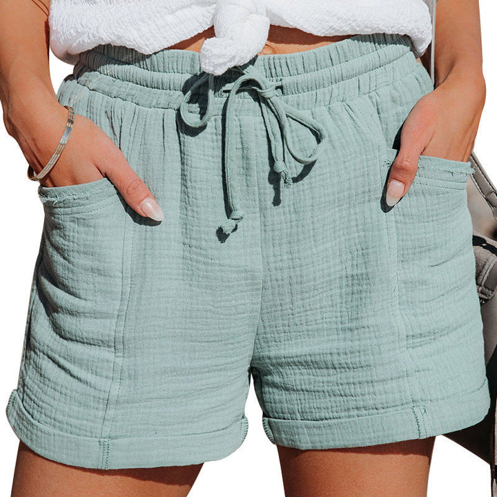 Sage green textured cotton shorts with an elastic drawstring waist, side pockets, and cuffed hems.