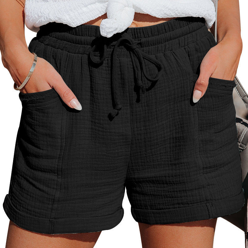 Black textured cotton shorts with an elastic drawstring waist, side pockets, and cuffed hems for a relaxed fit.