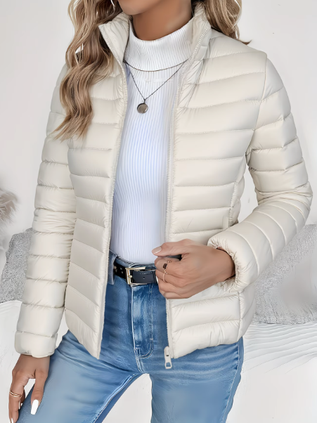 Cream lightweight quilted puffer jacket with a high stand collar and full-length zip, worn over a white ribbed top.
